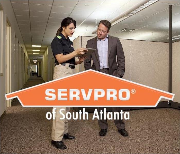 SERVPRO employee standing in office next to a person reviewing plans