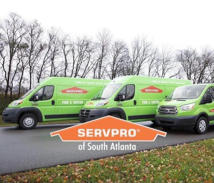 three green SERVPRO trucks lined up on a side street